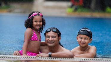 Father and children enjoying leisure hours in the pool